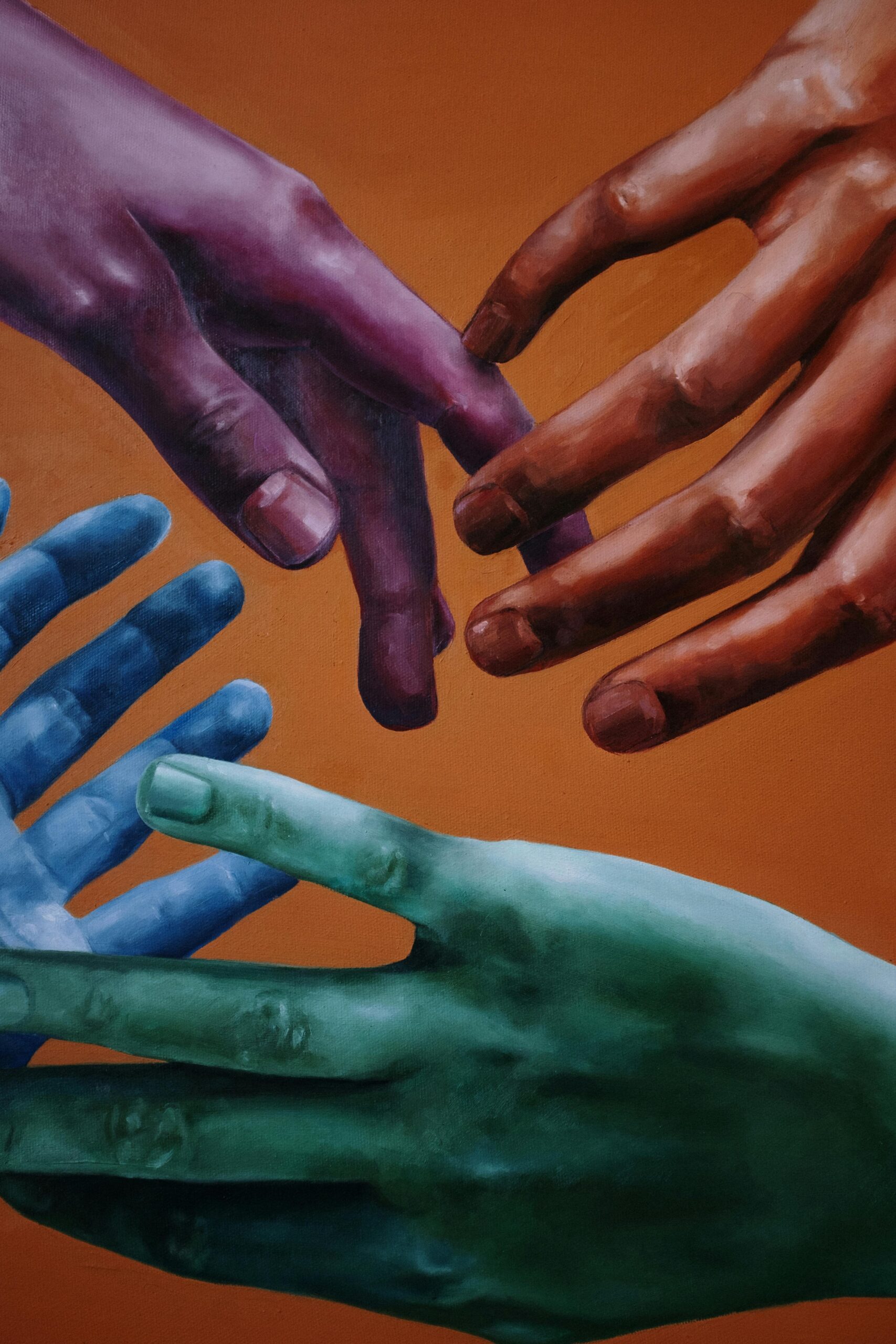 Red, purple, blue, and greens hands touching and with fingers interlaced